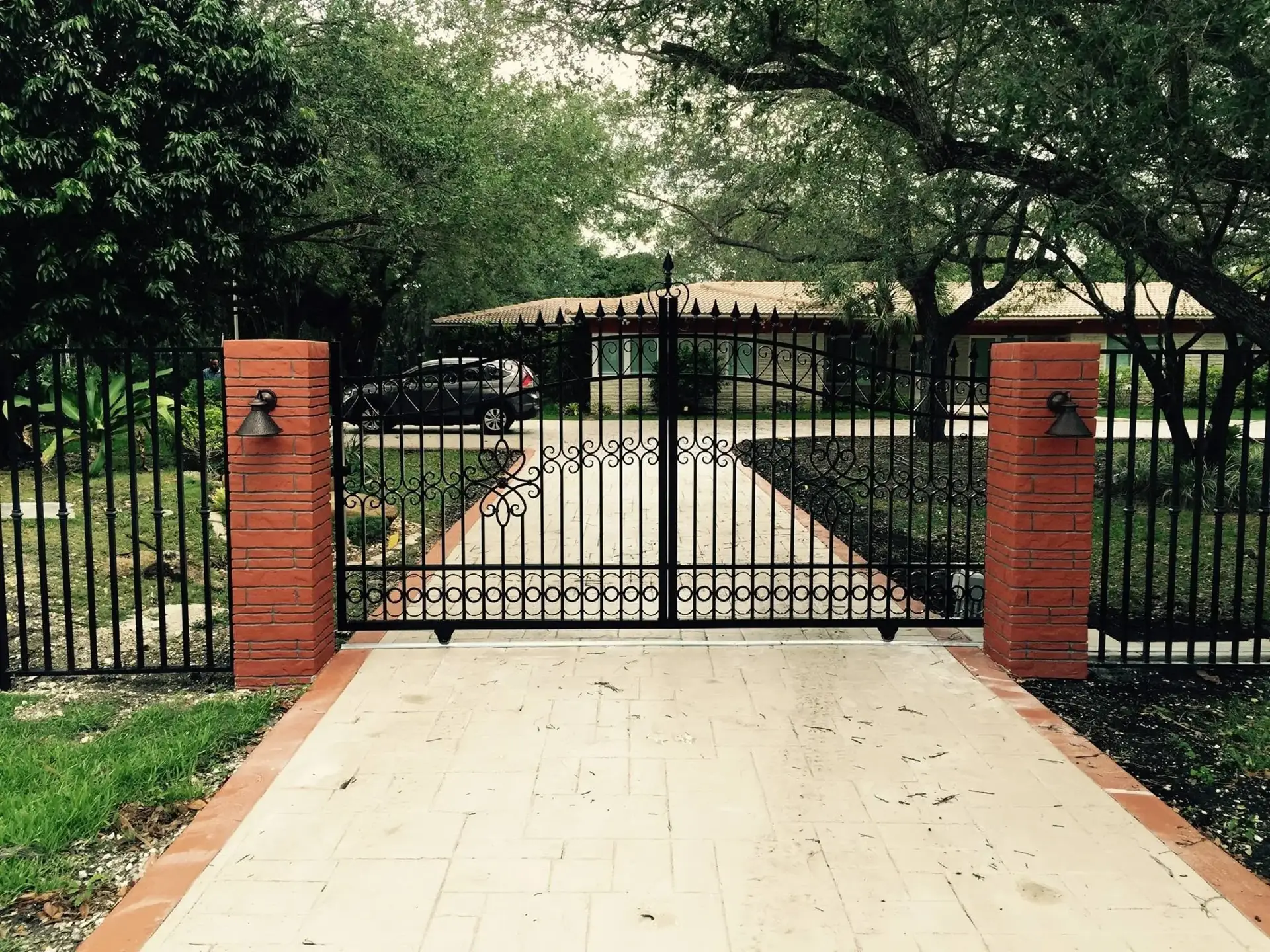 Ornamental aluminum driveway gate between brick pillars in Miami