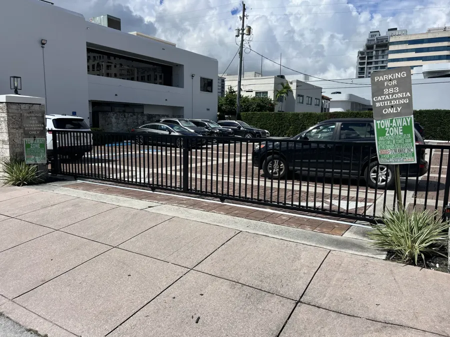 Commercial aluminum picket access gate with parking signage at a Miami-Dade building