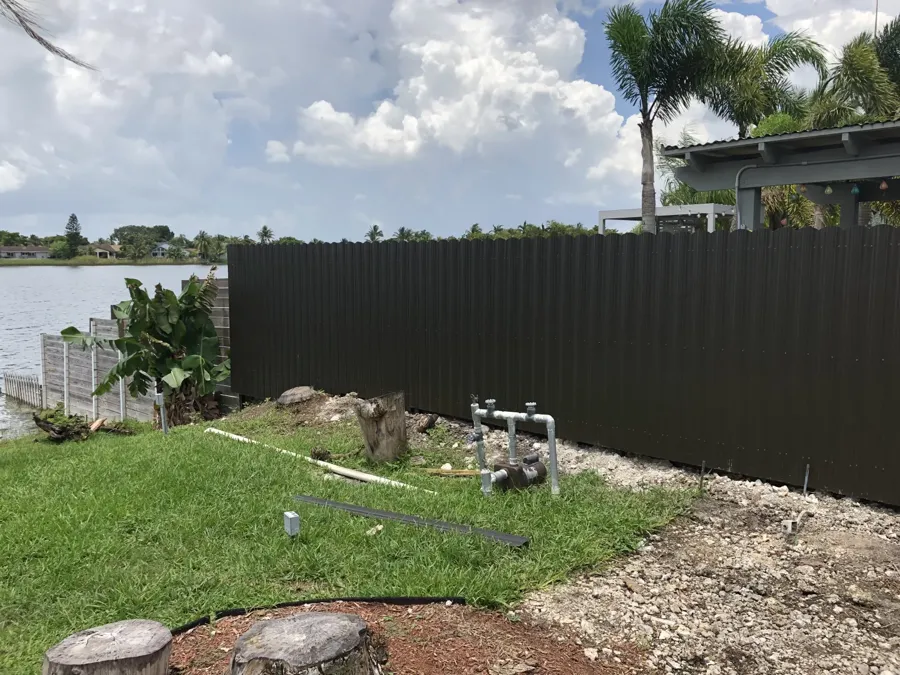 Dark Dura Fence metal privacy fence installed along a Miami waterfront property